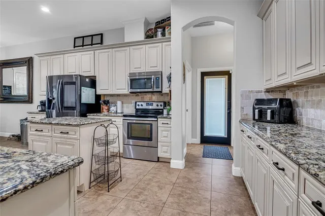 a kitchen with stainless steel appliances granite countertop a stove top oven a sink dishwasher a refrigerator and a oven