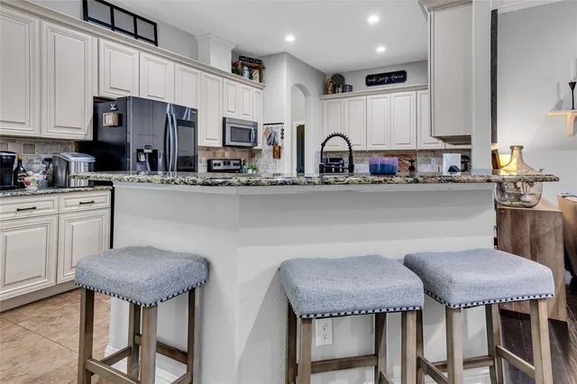 a kitchen with stainless steel appliances granite countertop a table chairs microwave and cabinets
