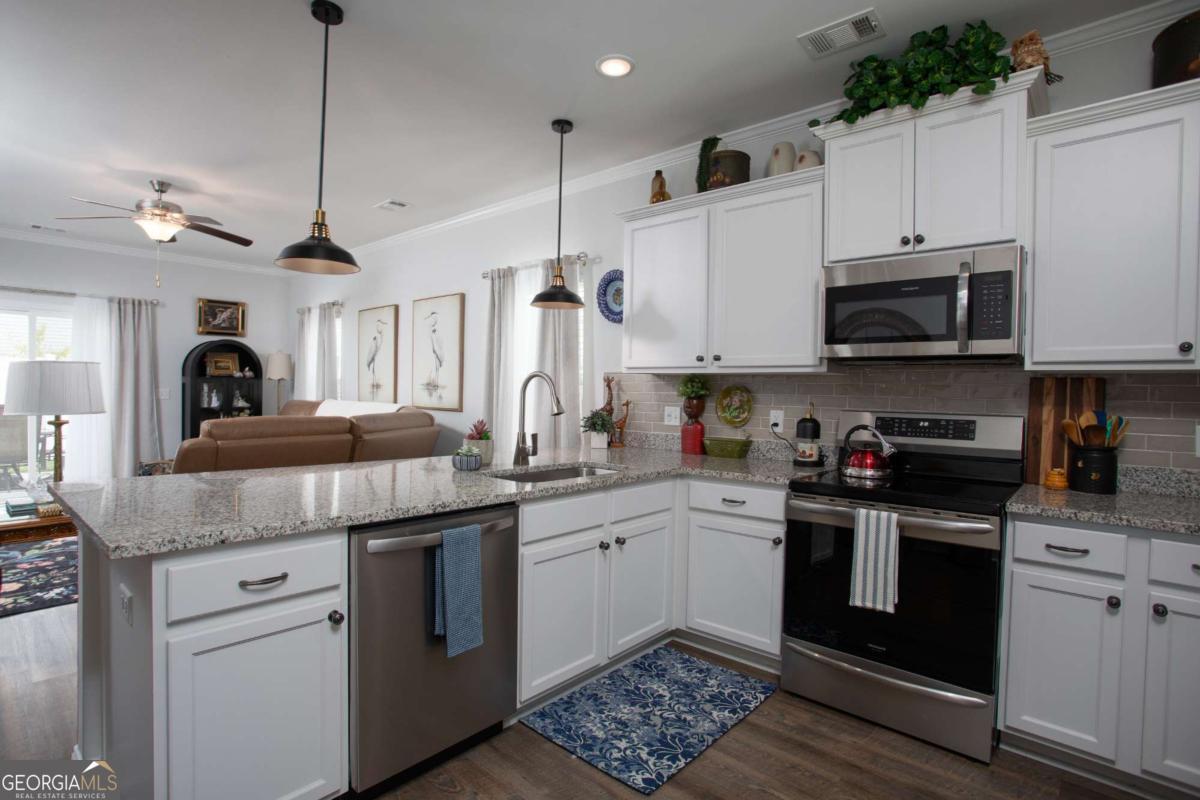 439 Gov Treutlen Circle Pooler, GA 31322 - Photo 5 of 21 a kitchen with granite countertop a sink and stainless steel appliances