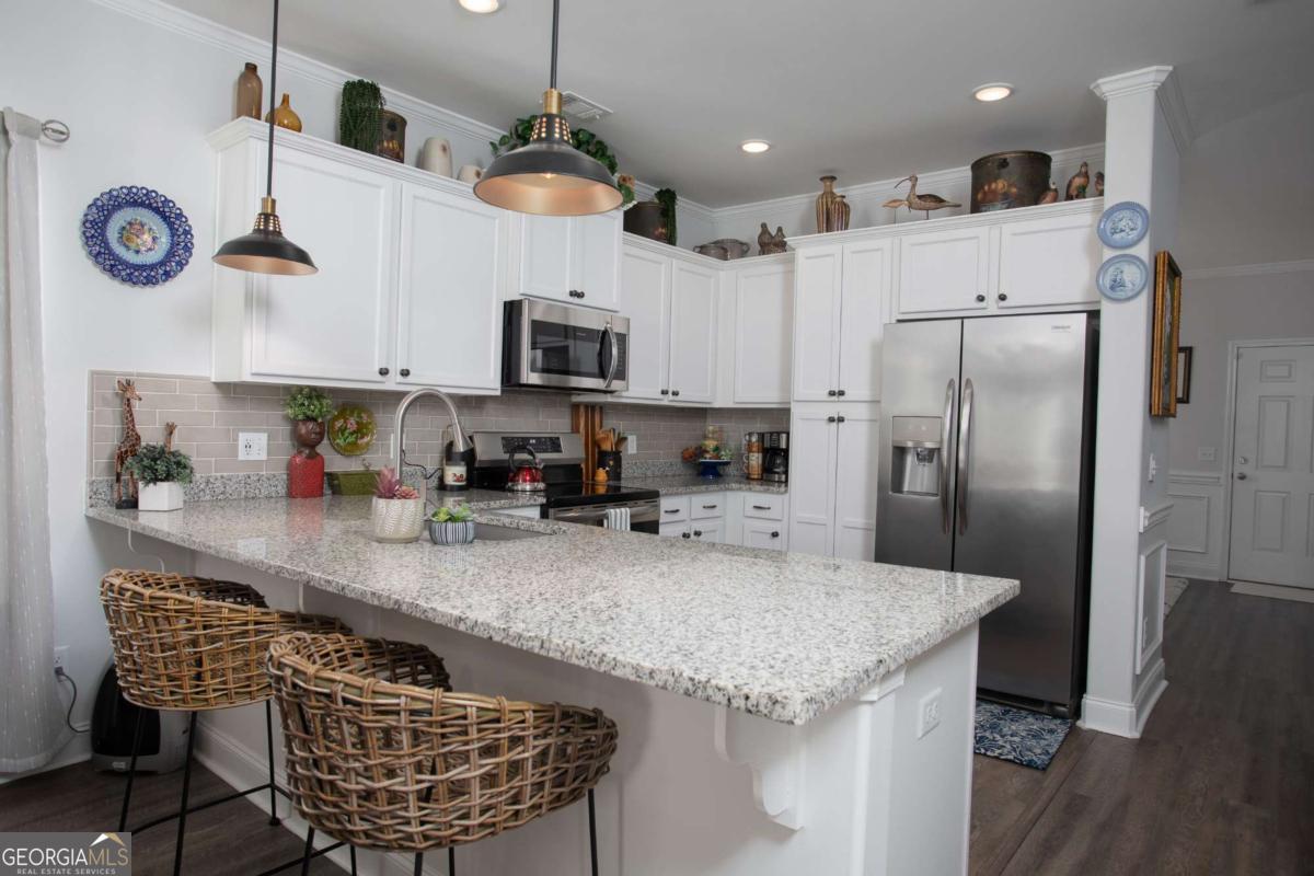 439 Gov Treutlen Circle Pooler, GA 31322 - Photo 6 of 21 a kitchen with kitchen island granite countertop a sink a center island stainless steel appliances and cabinets