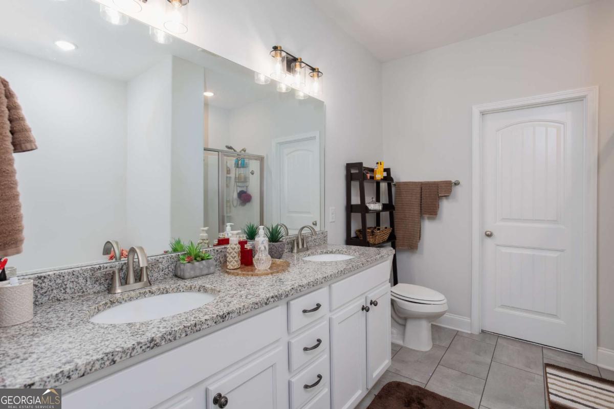 439 Gov Treutlen Circle Pooler, GA 31322 - Photo 10 of 21 a bathroom with a granite countertop sink a toilet and a mirror