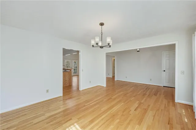a view of an empty room with wooden floor and a kitchen