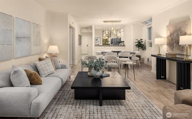 a living room with furniture potted plant kitchen view and a window