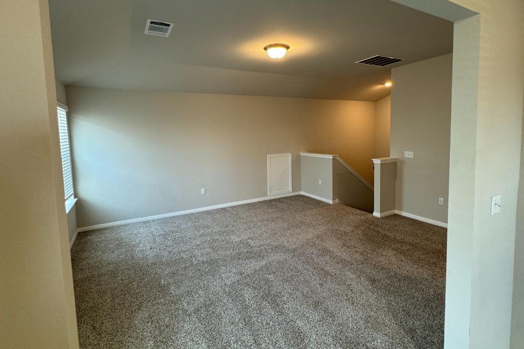 12604 Dairywork Road Buda, TX 78610 - Photo 12 of 20 A spacious upper-level living area with neutral carpeting provides an adaptable space for comfort and leisure.
