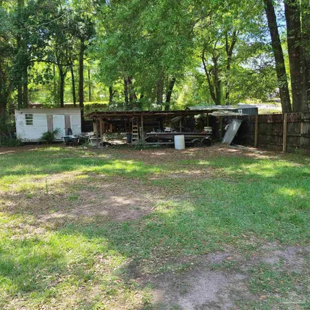 a view of a backyard with table and chairs and potted plants and large trees