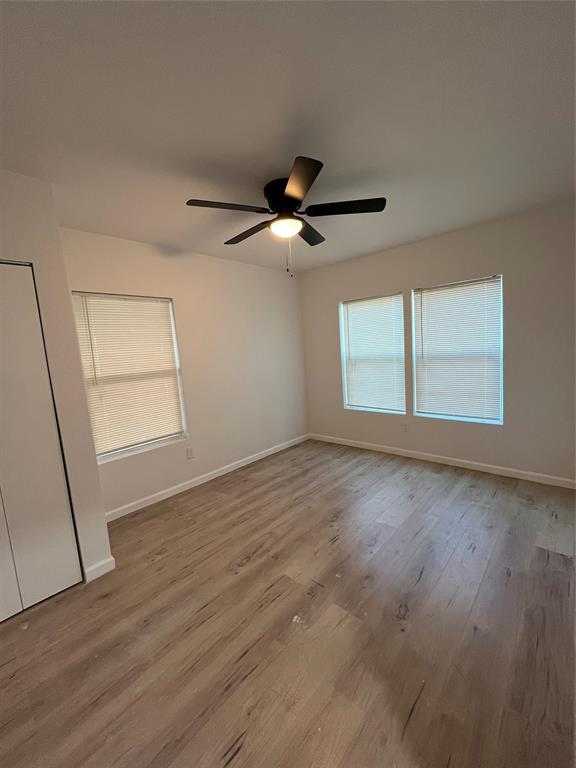 3919 Carl Street Dallas, TX 75210 - Photo 3 of 17 an empty room with wooden floor fan and windows