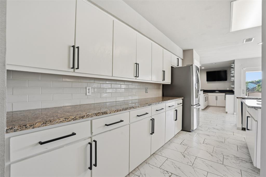 704 Timberview Court North Fort Worth, TX 76112 - Photo 17 of 40 a kitchen with granite countertop white cabinets and stainless steel appliances