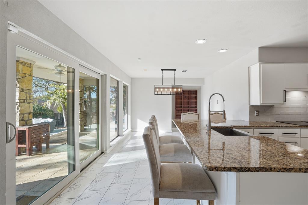 704 Timberview Court North Fort Worth, TX 76112 - Photo 19 of 40 a kitchen with granite countertop a stove a sink a dining table and chairs