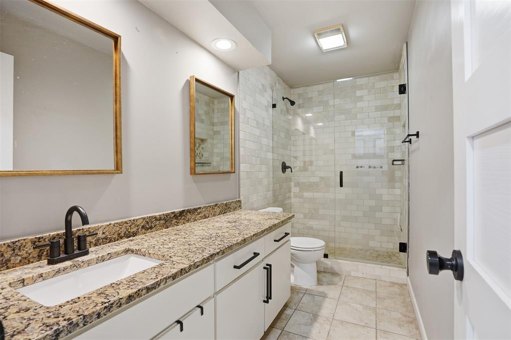704 Timberview Court North Fort Worth, TX 76112 - Photo 21 of 40 a bathroom with a granite countertop sink a toilet and shower