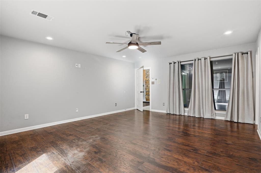 704 Timberview Court North Fort Worth, TX 76112 - Photo 29 of 40 an empty room with wooden floor ceiling fan and windows