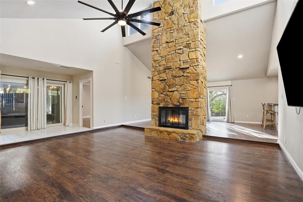 704 Timberview Court North Fort Worth, TX 76112 - Photo 8 of 40 an empty room with wooden floor a fireplace and windows