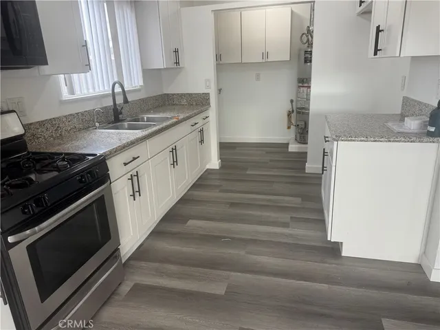 an empty room with wooden floor and windows with curtains
