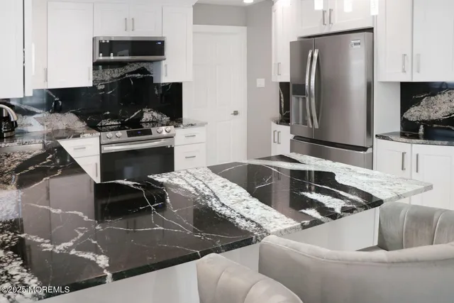 a kitchen with stainless steel appliances kitchen island granite countertop a sink and a stove