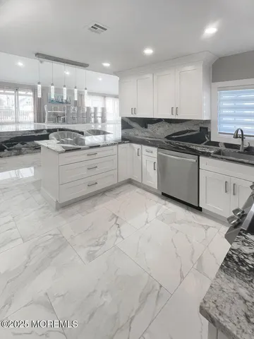 a large kitchen with stainless steel appliances kitchen island granite countertop a sink and cabinets