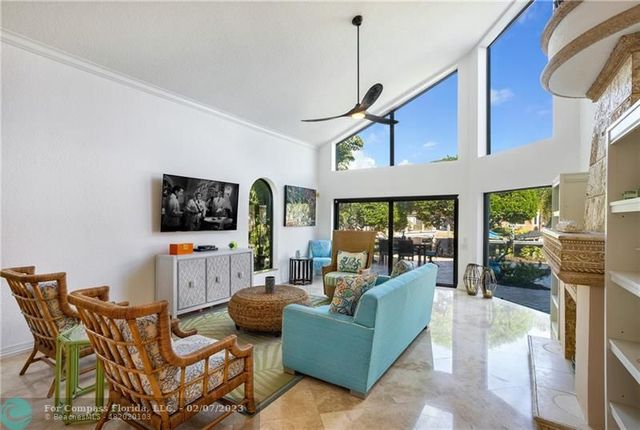 a living room with furniture a flat screen tv and a floor to ceiling window