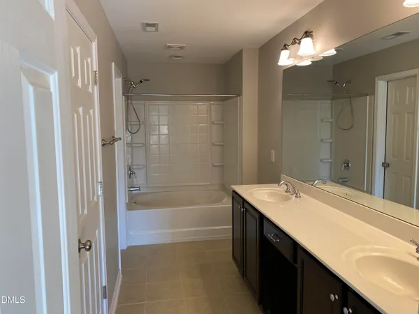 a bathroom with a sink double vanity mirror and a bathtub
