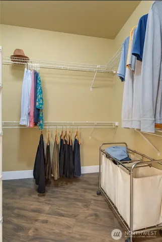 a walk in closet with wooden floor