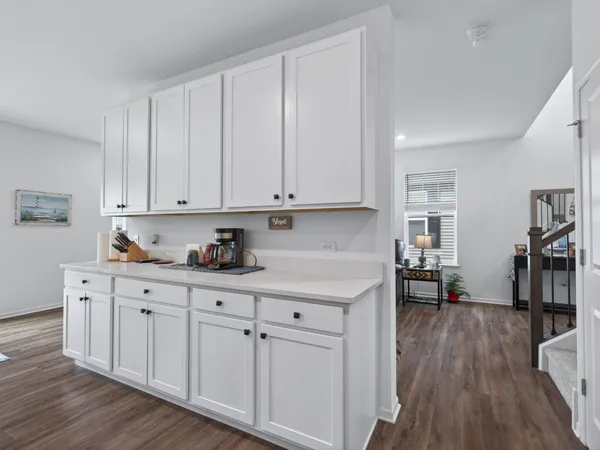 a kitchen with white cabinets and wooden floor