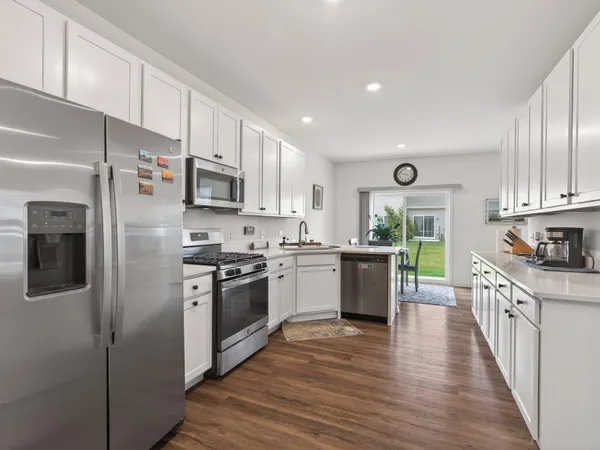 a kitchen with stainless steel appliances granite countertop a stove top oven a refrigerator a sink and dishwasher with wooden floor