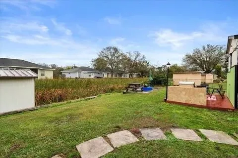 a view of a white house with a big yard and large trees