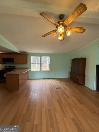 a view of empty room with wooden floor and fan