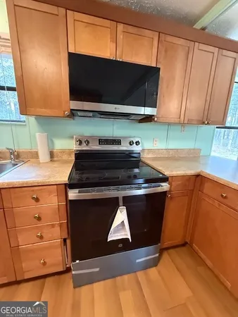 a kitchen with stainless steel appliances a stove a microwave a sink and cabinets