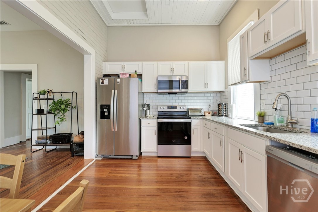 309 West 33rd Street Savannah, GA 31401 - Photo 23 of 35 Updated kitchen with white cabinetry, granite countertops, stainless steel appliances, and abundant natural light.