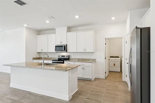 a kitchen with stainless steel appliances granite countertop a refrigerator sink and stove