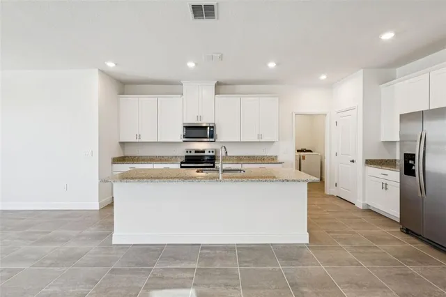 a large kitchen with stainless steel appliances a refrigerator a stove top oven and a sink