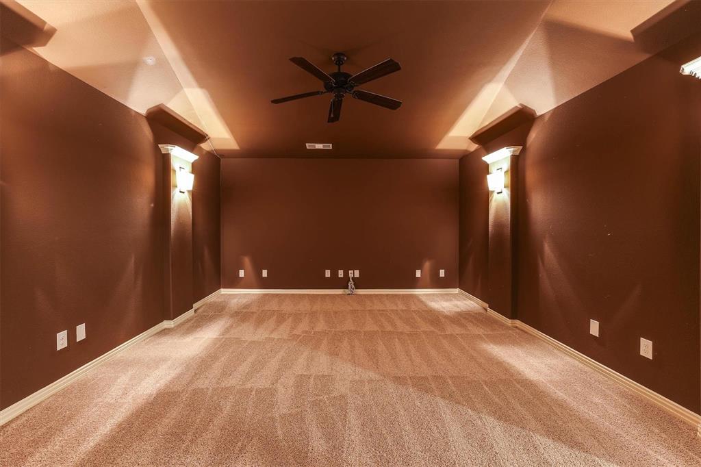 419 Rio Grande Drive Irving, TX 75039 - Photo 19 of 29 Spacious room featuring neutral carpet flooring, dark accent walls, a ceiling fan, and decorative sconces