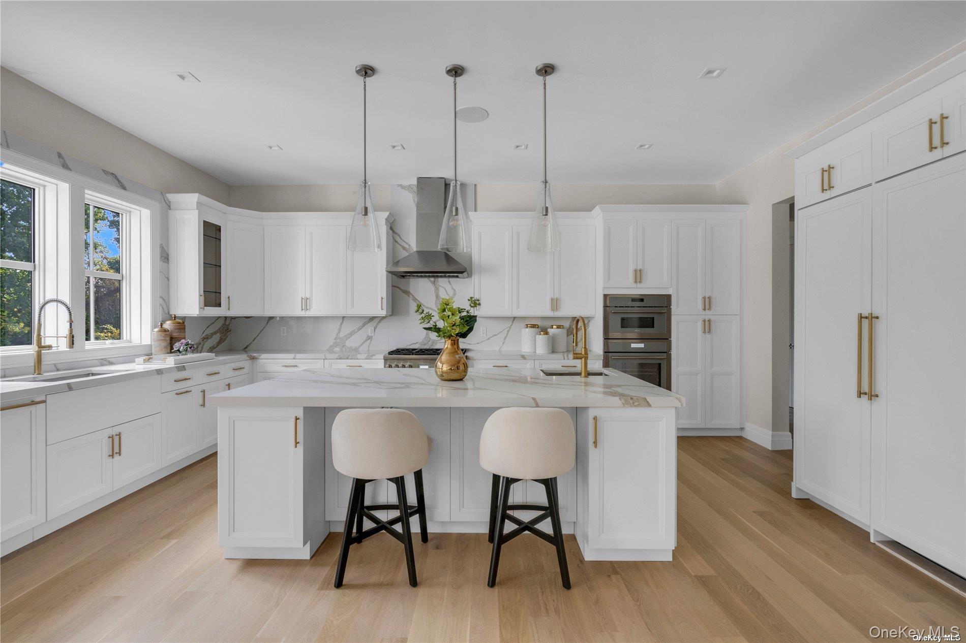 38 Cow Neck Road Sands Point, NY 11050 - Photo 14 of 48 a kitchen with stainless steel appliances kitchen island a table chairs in it and white cabinets