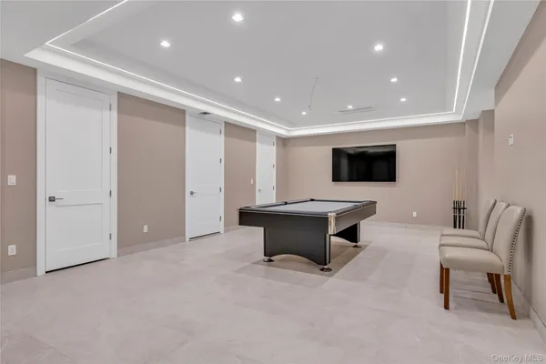 a living room with furniture a flat screen tv and a refrigerator
