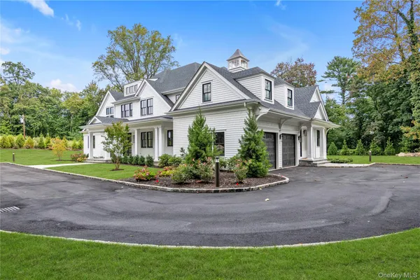 a view of a white house with a big yard plants and large trees