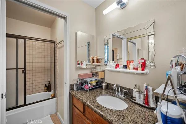 a bathroom with a granite countertop double vanity sink a mirror and shower