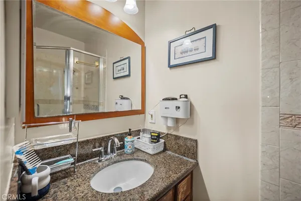 a bathroom with a granite countertop sink and a mirror
