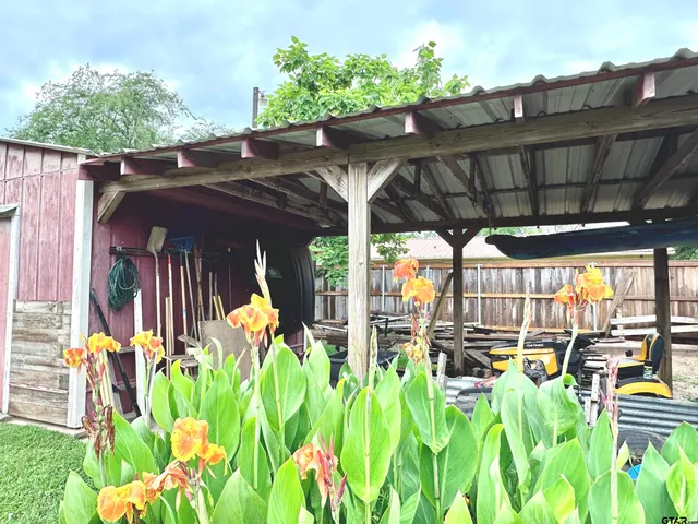 a view of a patio with table and chairs potted plants and floor to ceiling window and wooden fence