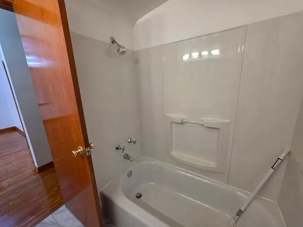 a view of an empty room with wooden floor and windows