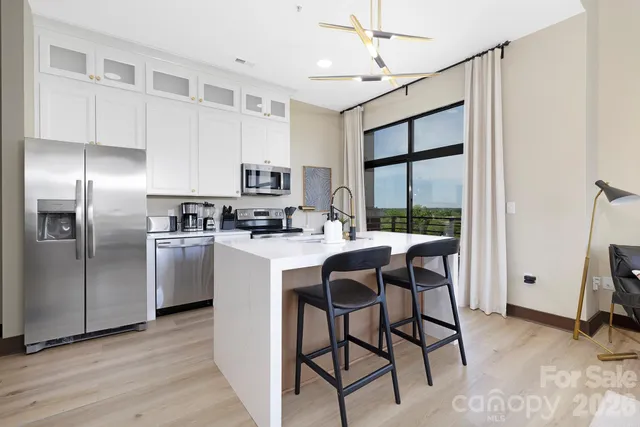 a kitchen with kitchen island a stove a refrigerator and a view of living room
