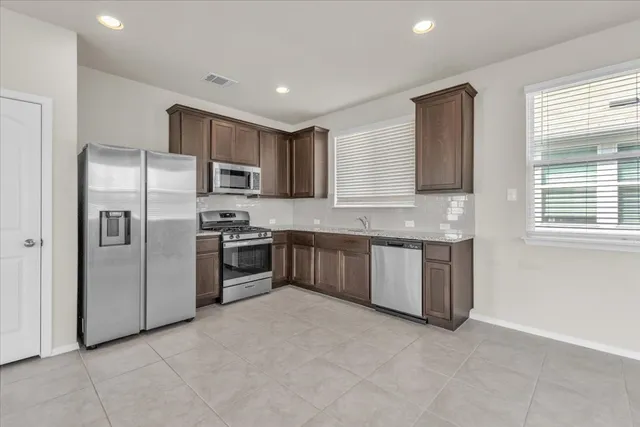 a kitchen with stainless steel appliances granite countertop a refrigerator a sink a stove a microwave and island