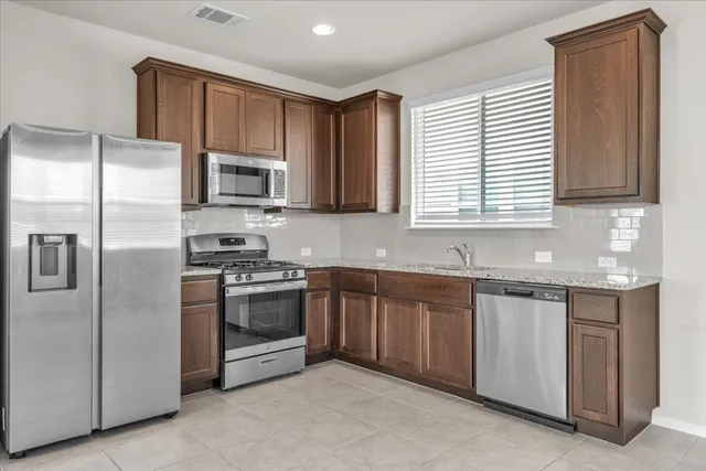 a kitchen with granite countertop stainless steel appliances a sink stove and refrigerator