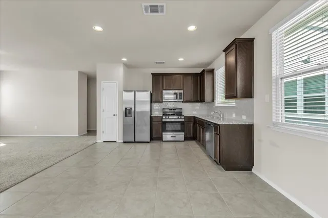 a large kitchen with stainless steel appliances granite countertop a stove a sink a refrigerator and a oven