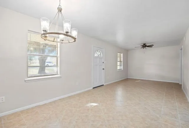 an empty room with chandelier fan