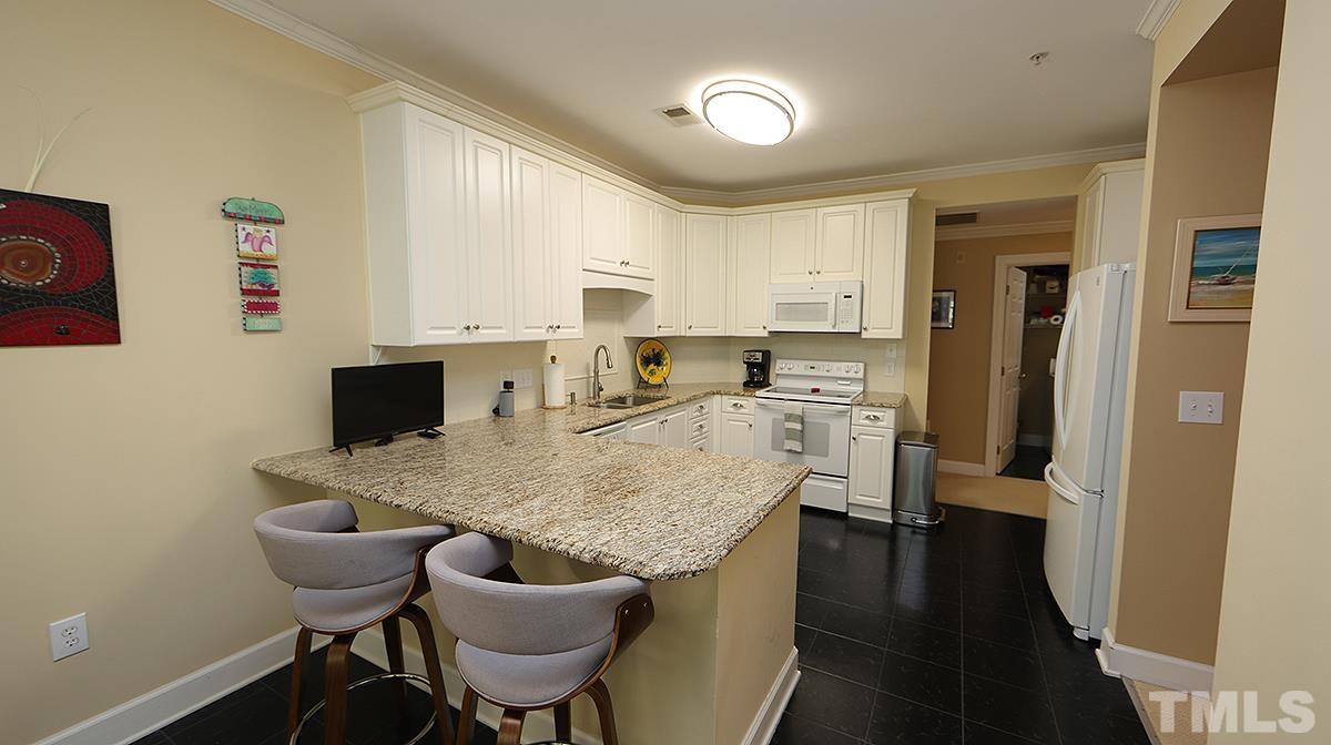100 Northbrook Drive, Unit 203 Raleigh, NC 27609 - Photo 11 of 39 a kitchen with a table chairs refrigerator and cabinets