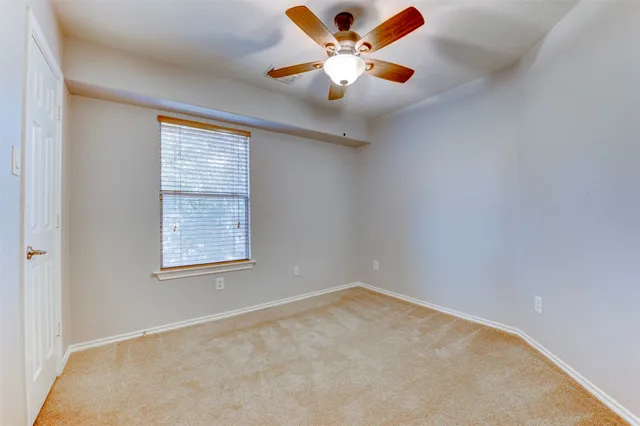 an empty room with a window and a fan