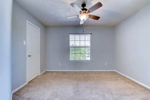 an empty room with a chandelier fan and windows