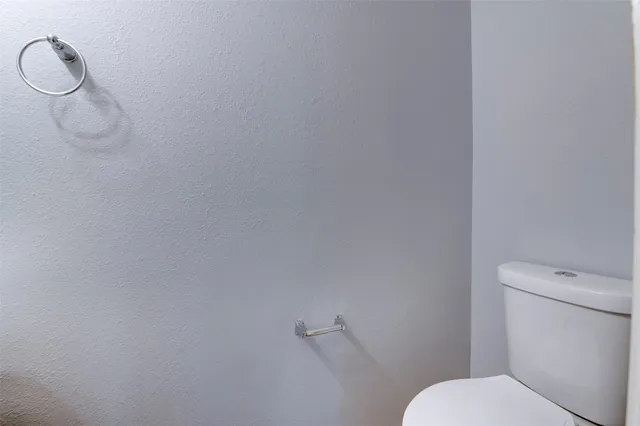 a white toilet sitting next to a white wall