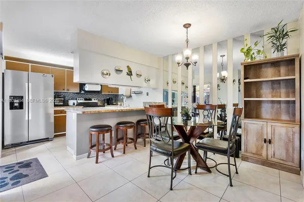 a kitchen with stainless steel appliances kitchen island granite countertop a table chairs and a refrigerator