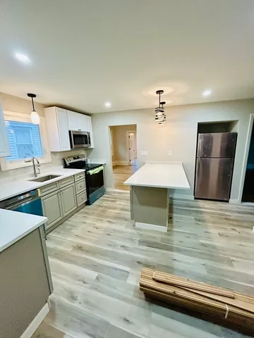 a kitchen with kitchen island stainless steel appliances a sink and a stove