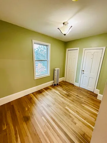 a view of an empty room with window and wooden floor