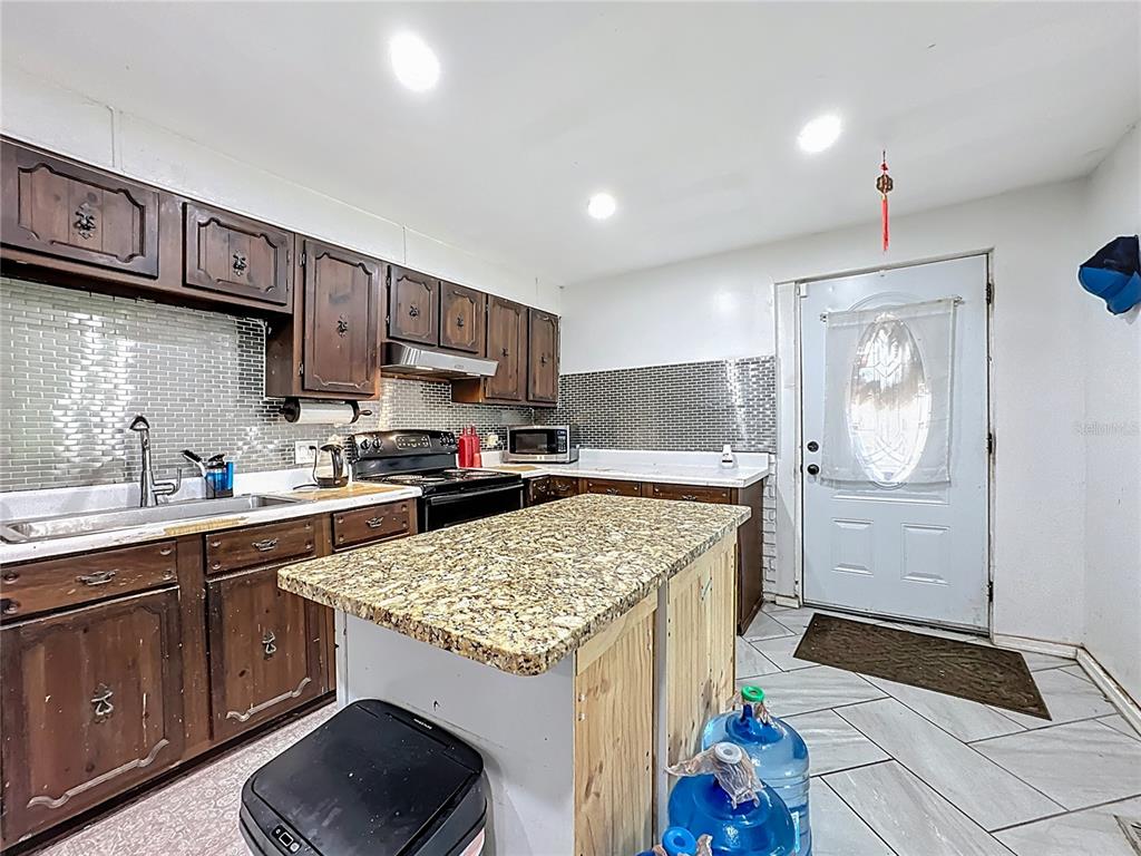 7717 Clarcona Ocoee Road, Unit LOT 1 Orlando, FL 32818 - Photo 15 of 36 a kitchen with a sink stove and cabinets